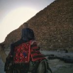 Student on a camel in front of a pyramid in Giza, Egypt