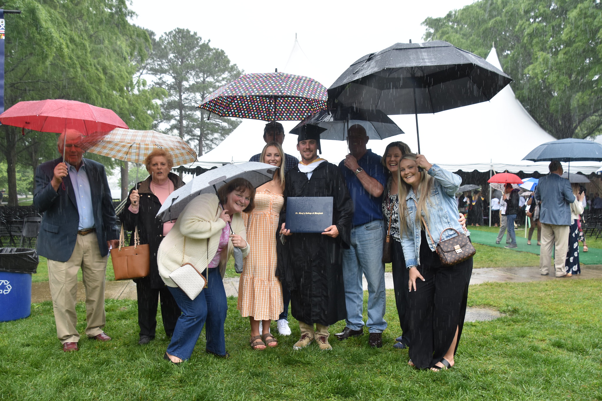 new graduate at commencement with family