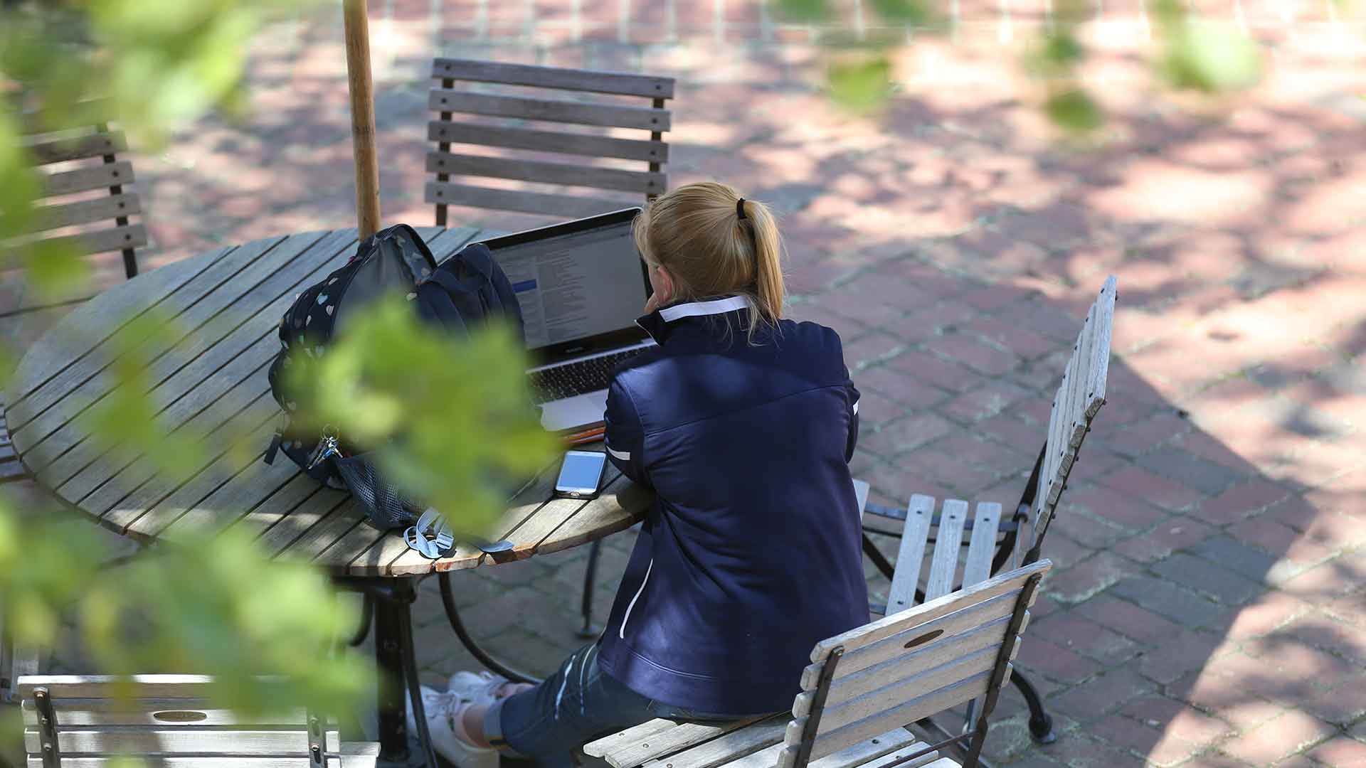SMCM student studying outdoors on the campus center patio