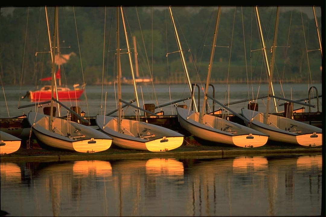 SMCM sailing team boats at sunset on the dock at the riverfront.