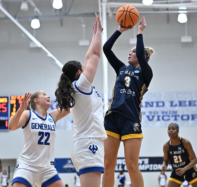 A St. Mary's College Honors College basketball player jumps to take a shot while two Washington and Lee University defenders try to block her during a game.