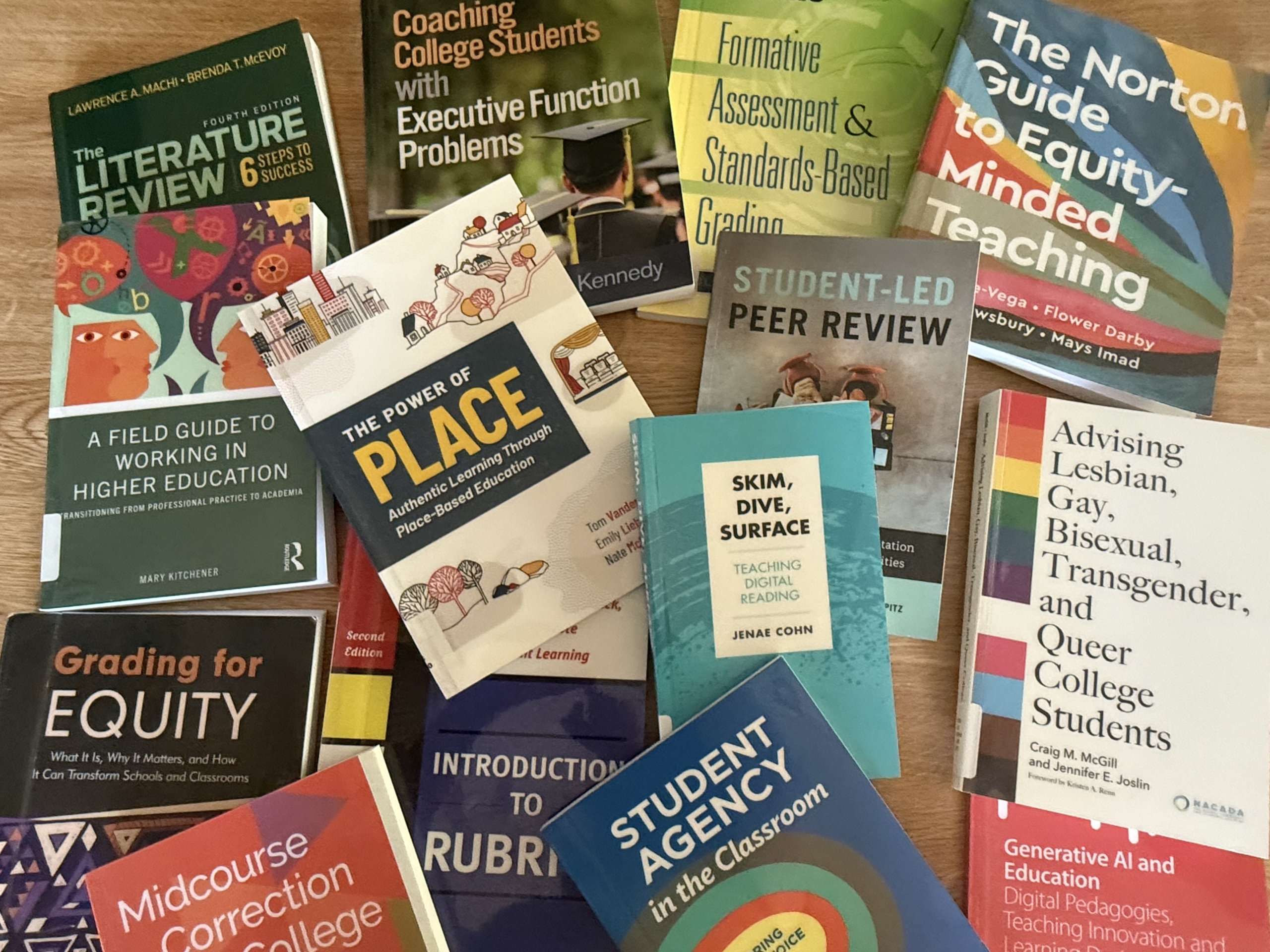 CITL Collection A collection of higher education books on topics such as teaching, grading, student engagement, peer review, rubrics, inclusivity, and executive function support is spread out on a surface.