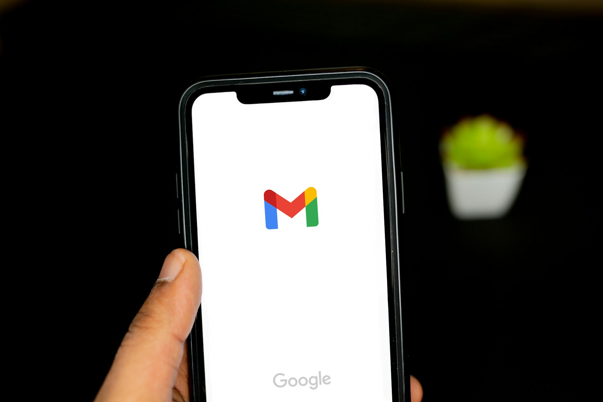 A stock photo of a hand holding a smartphone on a Google Gmail load screen