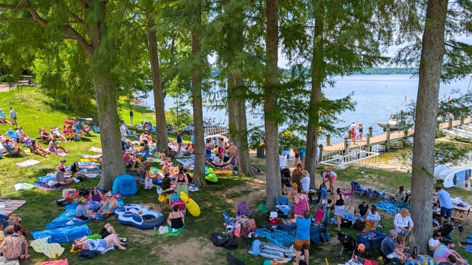 The crowd gathers under the trees at the waterfront during Alumni Weekend