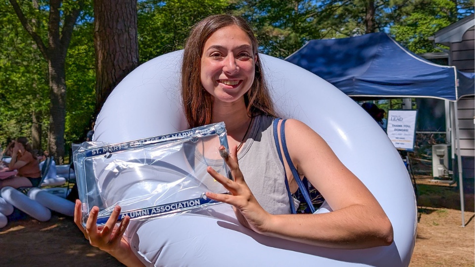 SMCM Almost Alumni Cookout 2025 - a student shows off her new alumni association license plate frame and inner tube