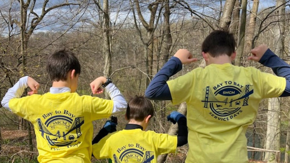Three young SMCM Bay to Bay volunteers pose heroically at a previous Philly Clean Up