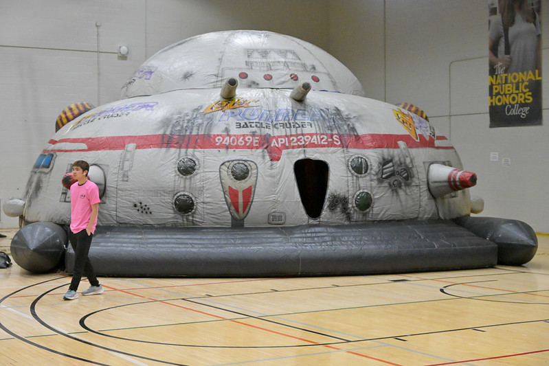 A student walks past a large inflatable structure shaped like a spaceship inside a gymnasium at the World Carnival.