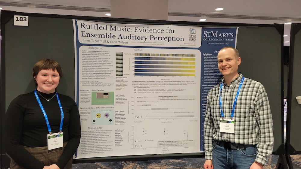 Two people stand in front of a research poster titled “Ruffled Music: Evidence for Ensemble Auditory Perception” at a conference. Both are wearing name badges and smiling.