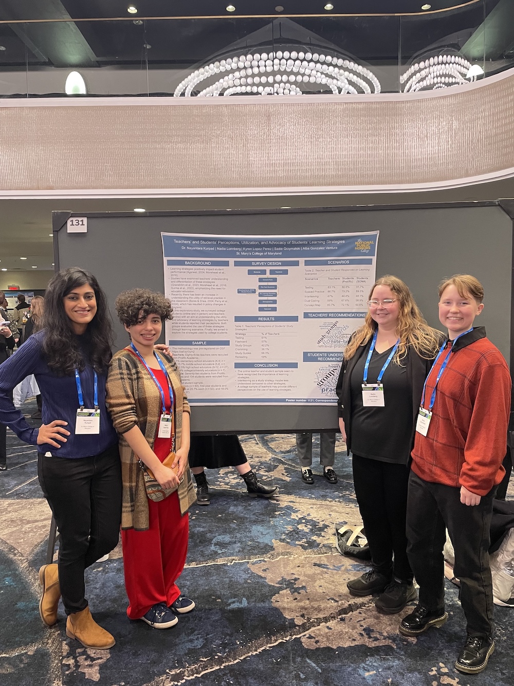 Four people stand and smile in front of a scientific research poster at a conference, each wearing a name badge.