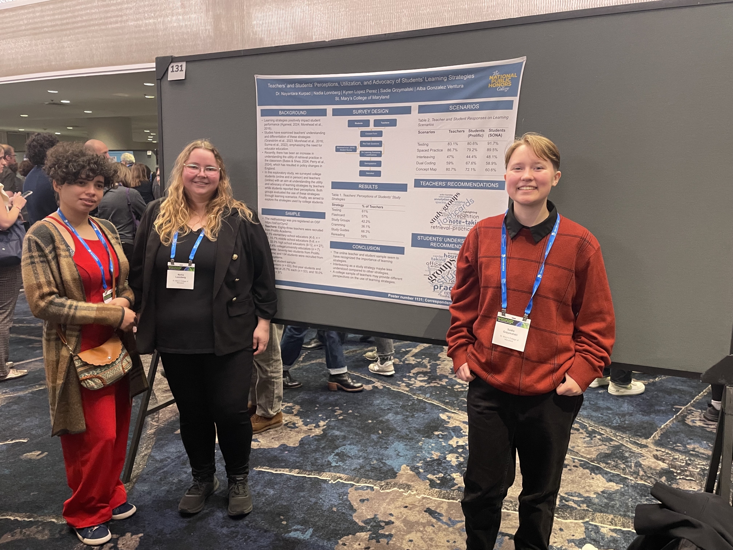 Three people stand in front of a large academic research poster at a conference, wearing name badges and blue lanyards.