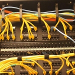 Image of cables in ports within a network switch closet.