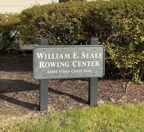 A sign reads "William E. Seale Rowing Center, 47508 Trinity Church Road," situated in front of bushes and grass.