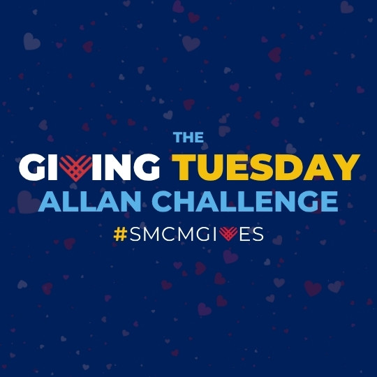Text reads: "THE GIVING TUESDAY ALLAN CHALLENGE #SMCMGIVES" on a blue background with faint heart shapes and a heart symbol replacing the "V" in "GIVING".