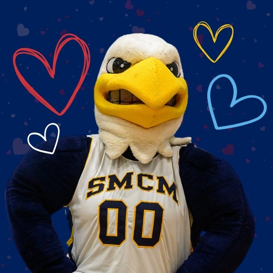 A person in an eagle mascot costume wearing a jersey labeled "SMCM 00" stands against a blue background with heart doodles.