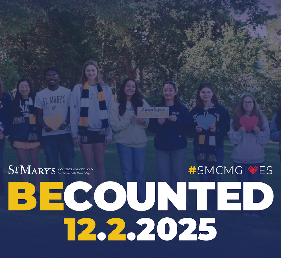 A group of nine students stand outdoors holding signs and hearts, promoting St. Mary's College of Maryland’s "Be Counted" event on December 2, 2025, for #SMCMGives.