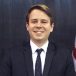 Eric Schroeder standing in front of an American flag.