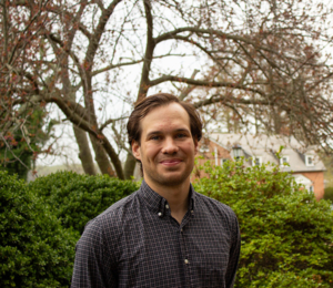 A person in a checked shirt stands proudly among the garden's leafless trees and shrubs, as if ready to receive awards for their dedication.