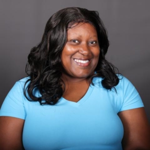 monica armstrong portrait A person in a light blue shirt, with a smile that suggests they've just received prestigious awards, stands proudly in front of a gray background.