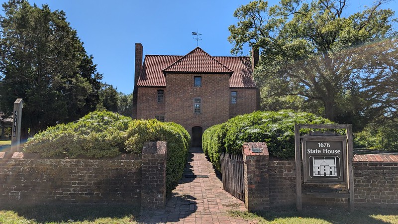A historic brick building with a red-tiled roof and symmetrical chimneys, labeled as the 1676 State House