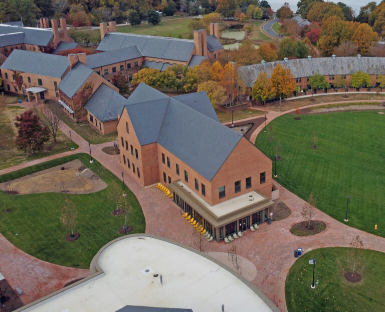 Aerial view of brick academic buildings surrounding a central lawn with trees in autumn foliage.