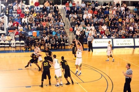 men in black and white uniforms play basketball on a court with people in the bleachers