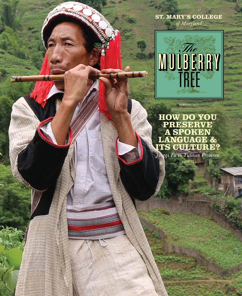 A man in traditional clothing plays a flute against a lush green hillside. The magazine cover for "The Mulberry Tree" features text about preserving language and culture, with "Spring 2017" noted.