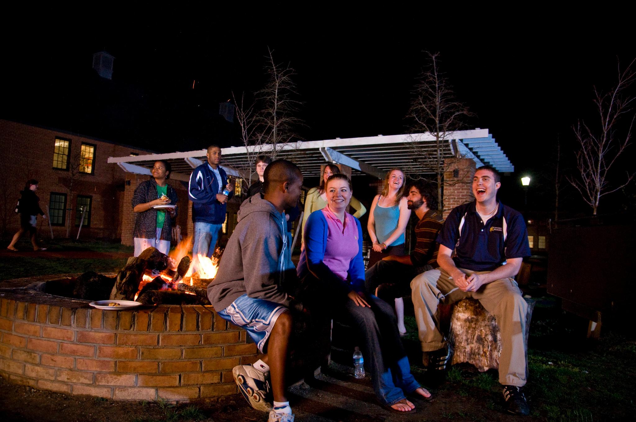 The fire pit with a large number of students gathered around