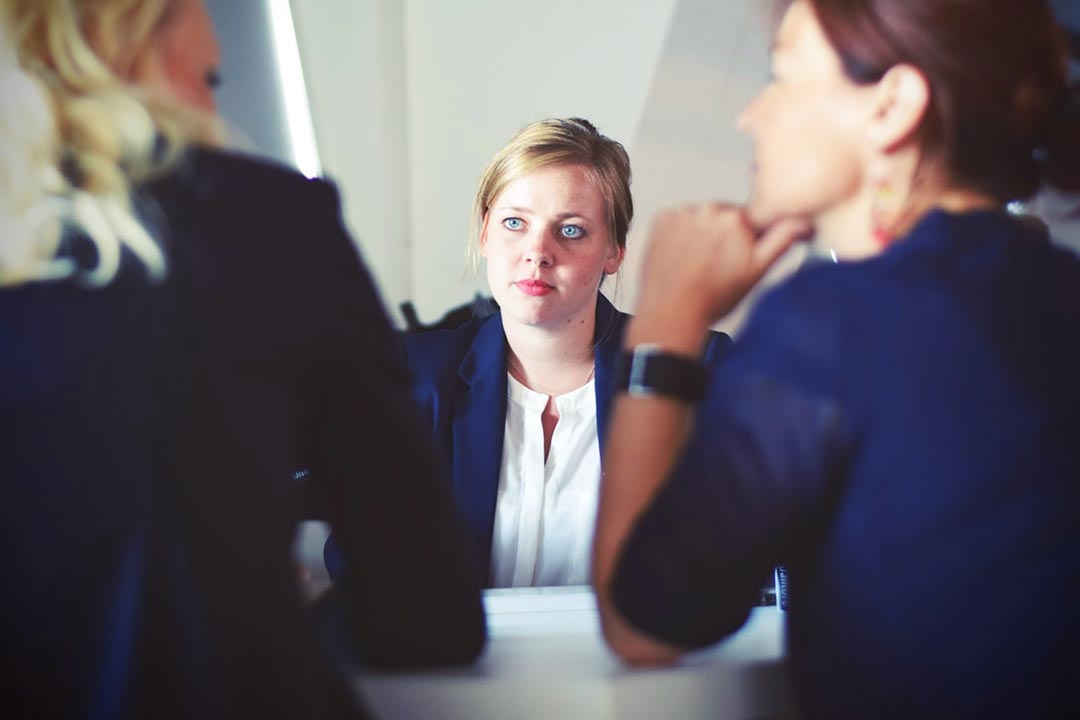 interview photo illustration: Interviewers in foreground, focus on candidate in center