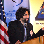 Dr. Ajay Singh Chaudhary lecturing from the podium at the Patuxent Defense Forum