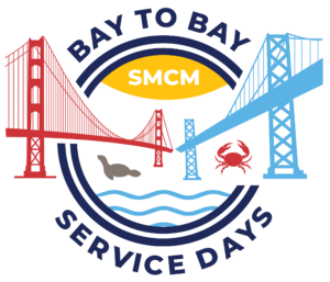 Illustration of red and blue bridges with a seal and crab below. Centered yellow oval with "SMCM" inside. Text reads "Bay to Bay Service Days." Wavy blue lines suggest water.