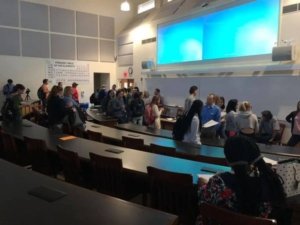 Faculty and students gather together in a lecture hall after a Research Opportunities Showcase