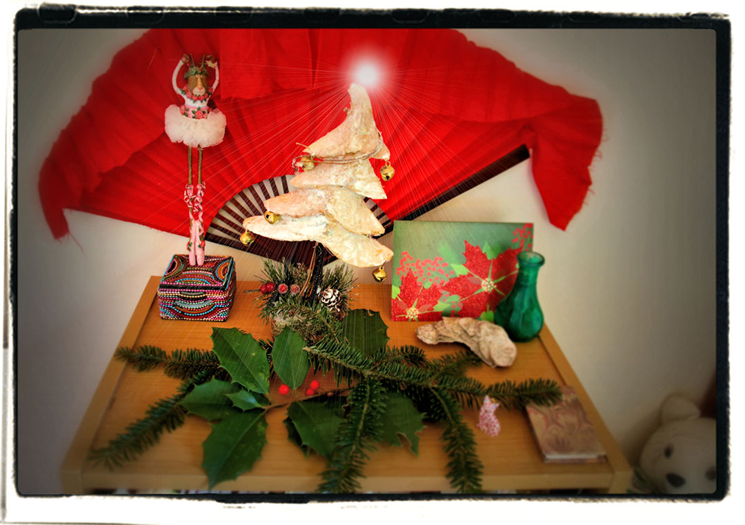 Merideth Taylor - Holiday display with red fan, dancer figurine, tree sculpture, card, and pine and holly garland Merideth Taylor - Holiday display with red fan, dancer figurine, tree sculpture, card, and pine and holly garland