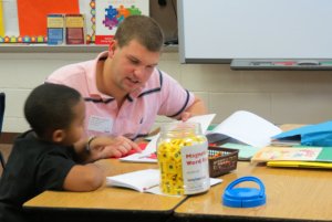 A student volunteer helping a young child with his school work