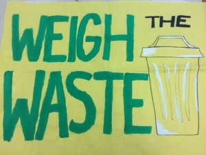 a sign with green lettering saying "weight the waste"