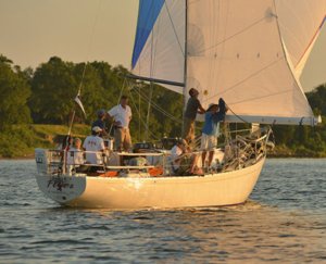 group of men operating a sailboat on a river at sunset