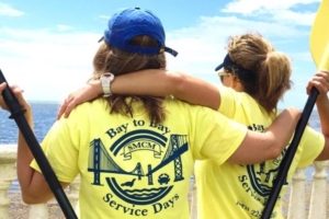 the back of two women in yellow shirts looking over a river