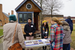 people talking across table in front of tiny house