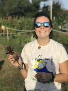 Girl wearing sunglasses with a beet in hand