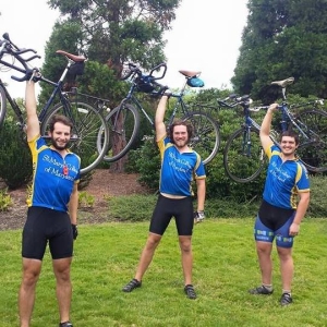 Three guys lifting bikes into the air