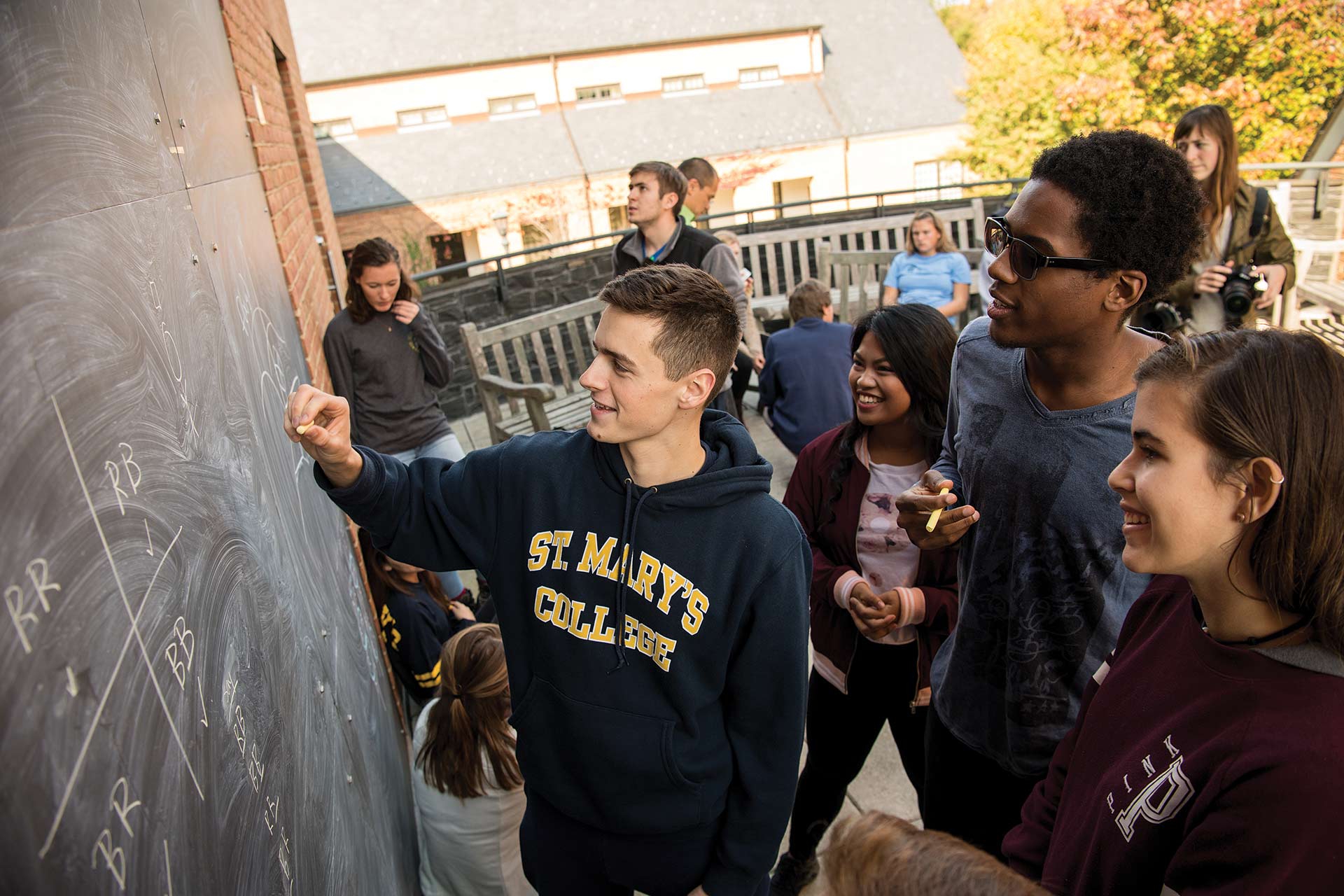 Students around an outdoor chalkboard working on a project.